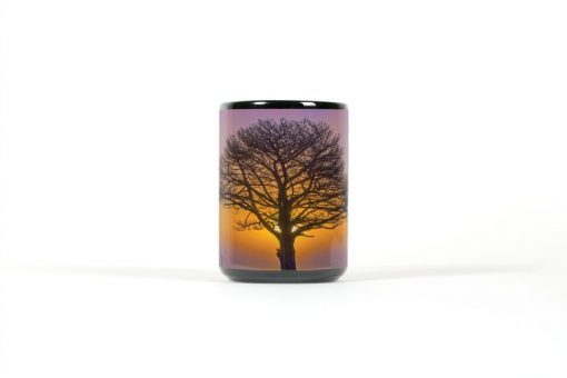 Center view of black mug with a tree silhouetted by a sunset